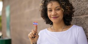 Photo of a smiling women with a sticker on the point of index finger that reads "I voted today."  Photo credit: LPETTET, Getty